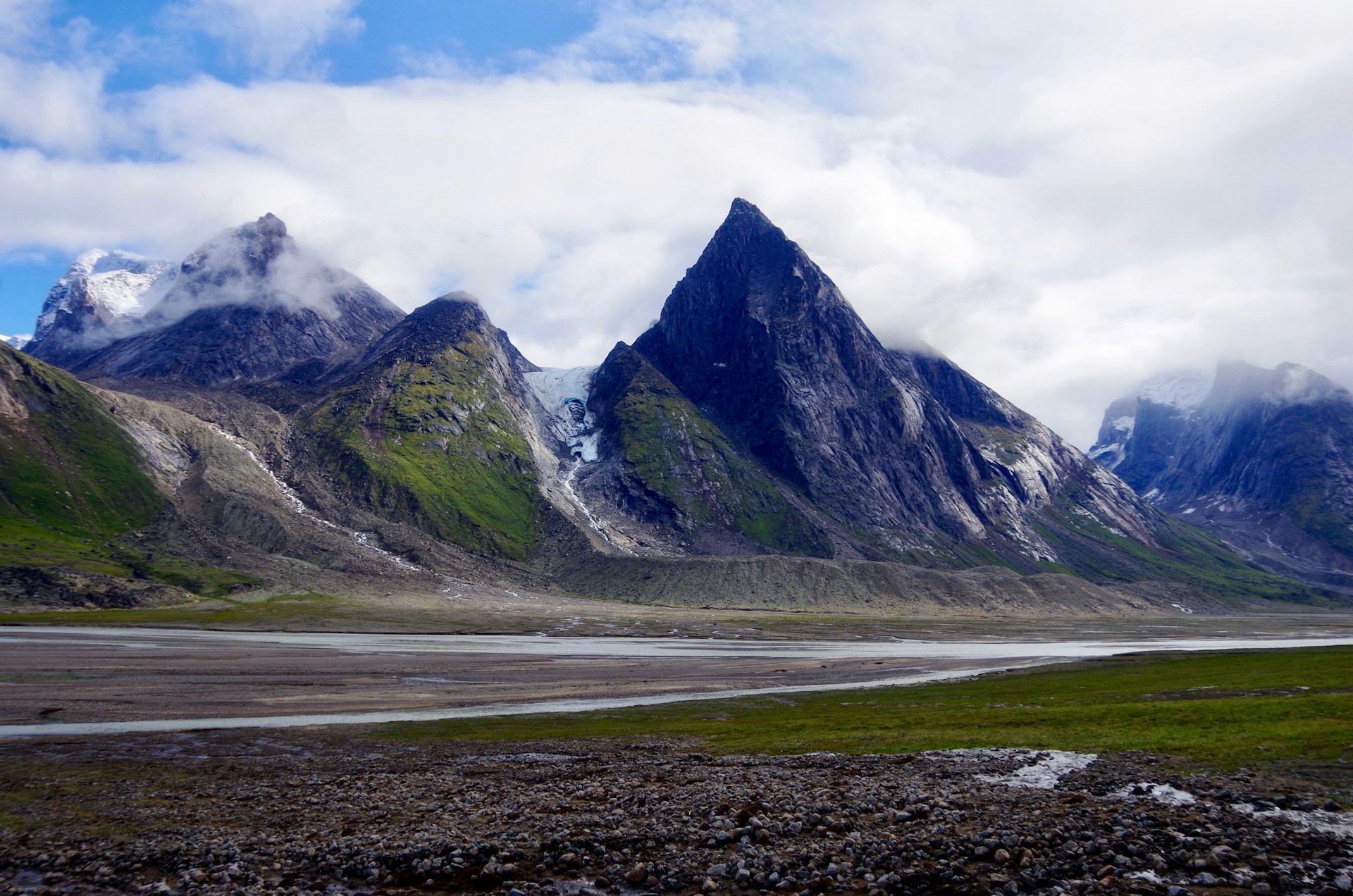 Dramatic Arctic landscape in Auyuittuq National Park with towering granite peaks and glacial valleys.