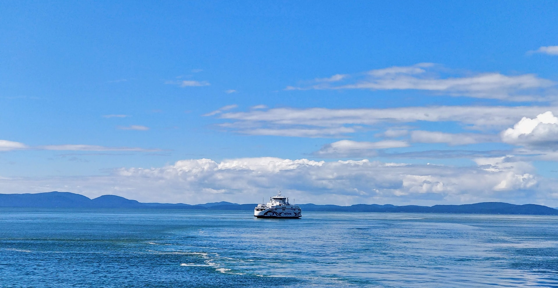A British Columbia Ferry seen from the side as it sails through the emerald green waters