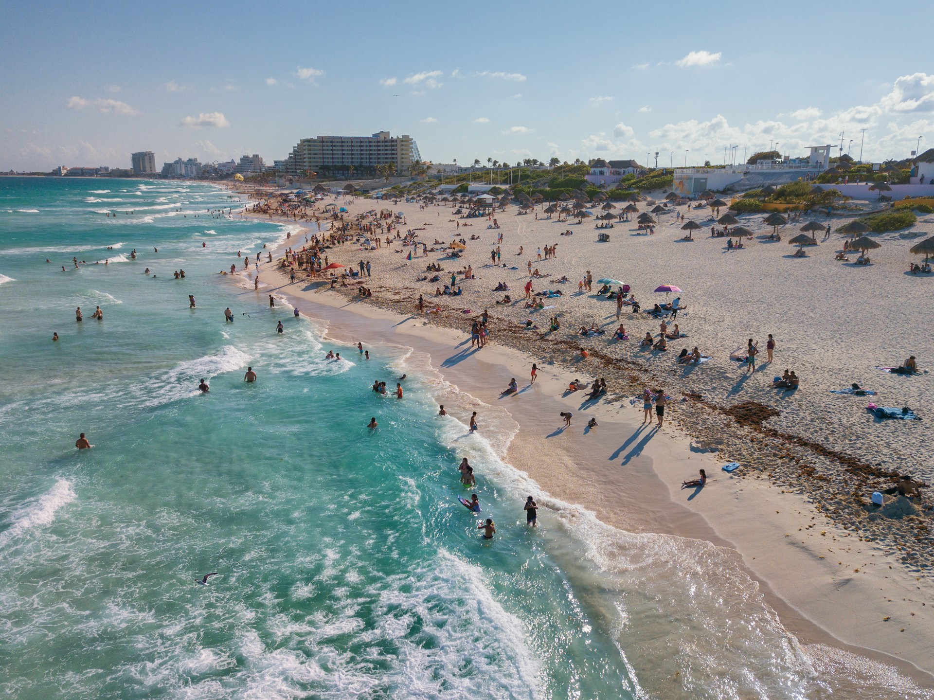 People relaxing and walking along a sunny beach in Cancun
