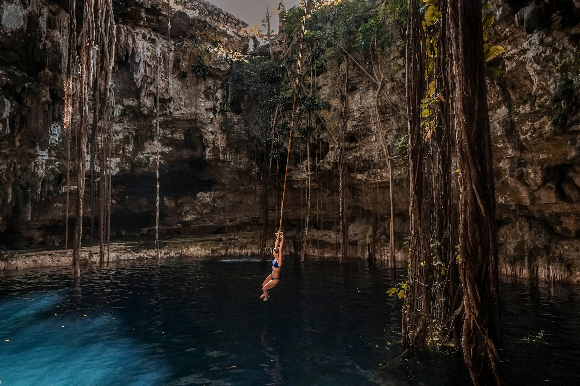 Crystal-clear cenote surrounded by lush jungle vegetation and limestone walls in Mexico