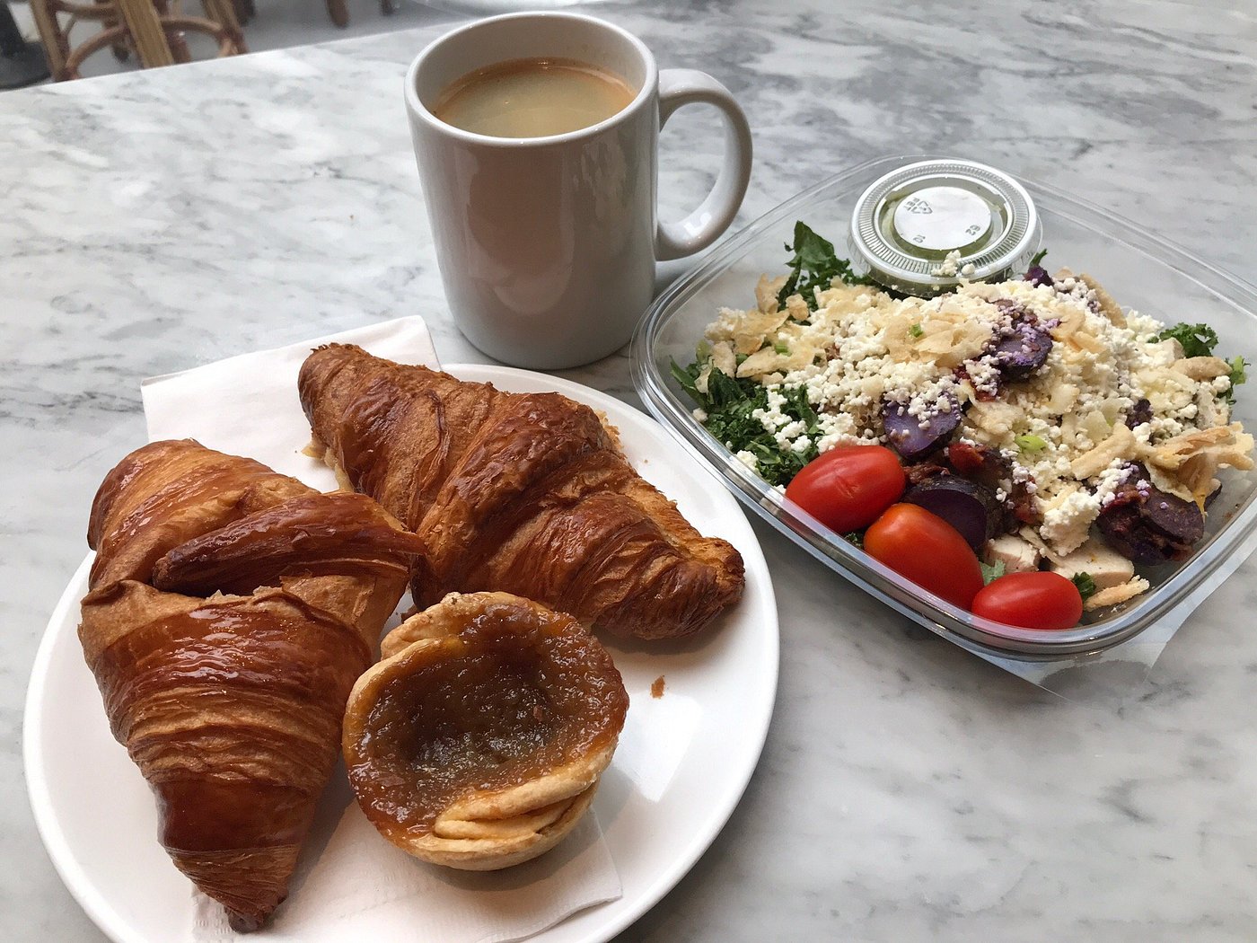 A freshly baked croissant resting on a plate at Dineen Coffee Co Toronto