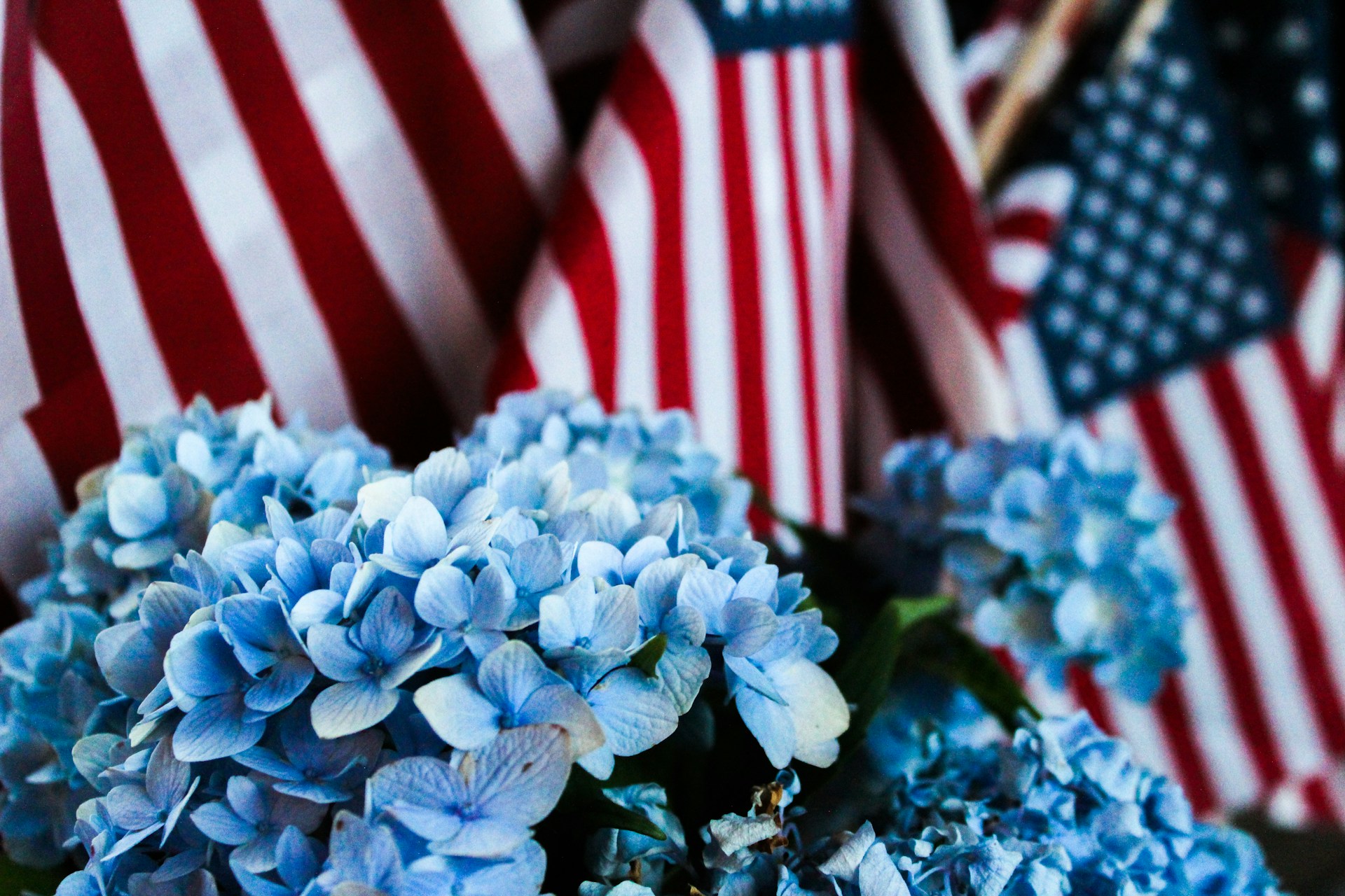 An American flag waves in the foreground of a vibrant Fourth of July celebration