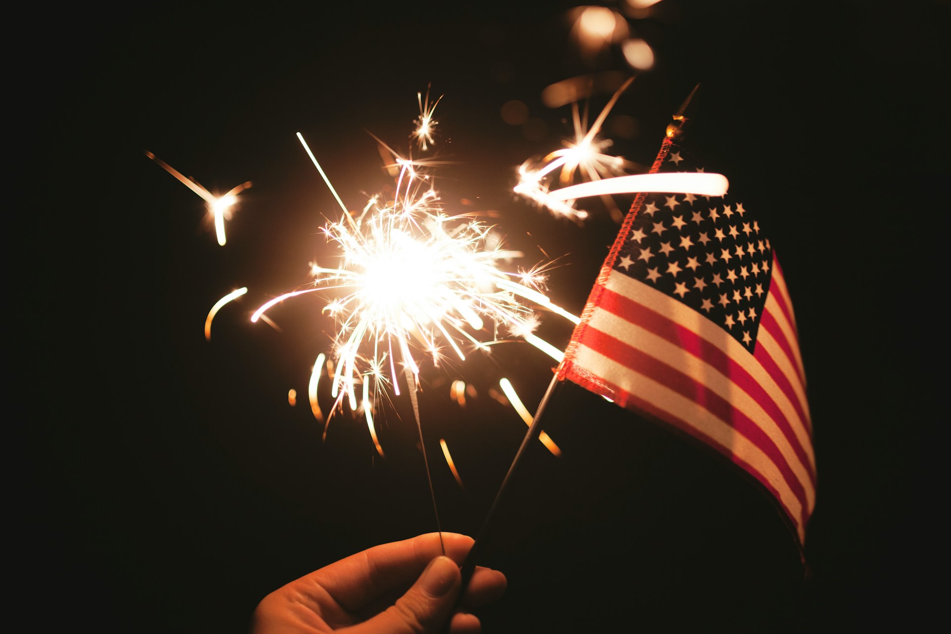 The flag is displayed in a festive setting, surrounded by decorations for the Fourth of July
