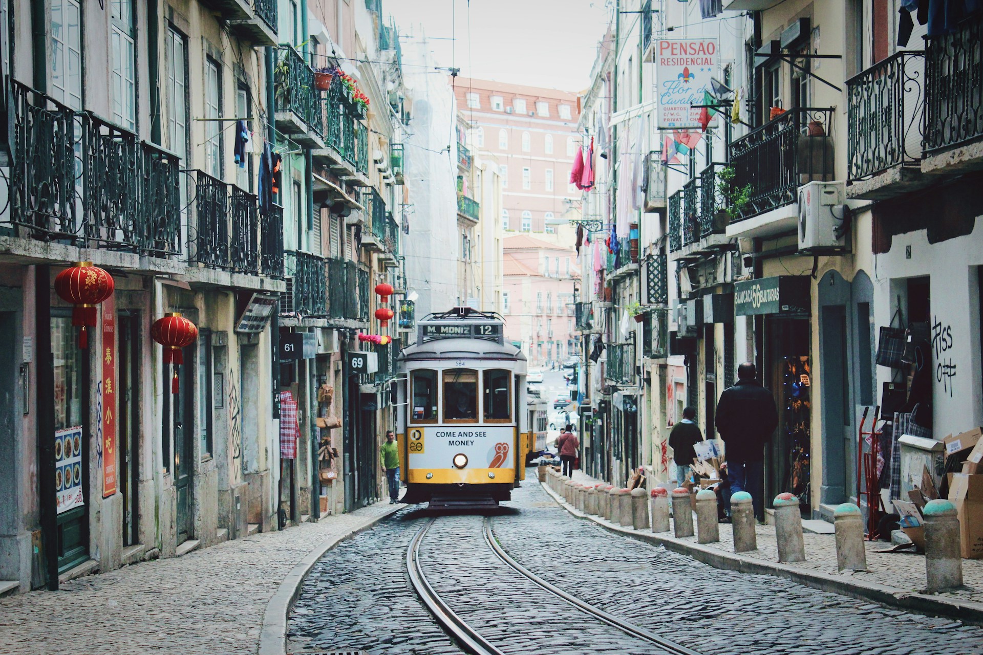 A front-facing view of a yellow tram on its tracks in Lisbon