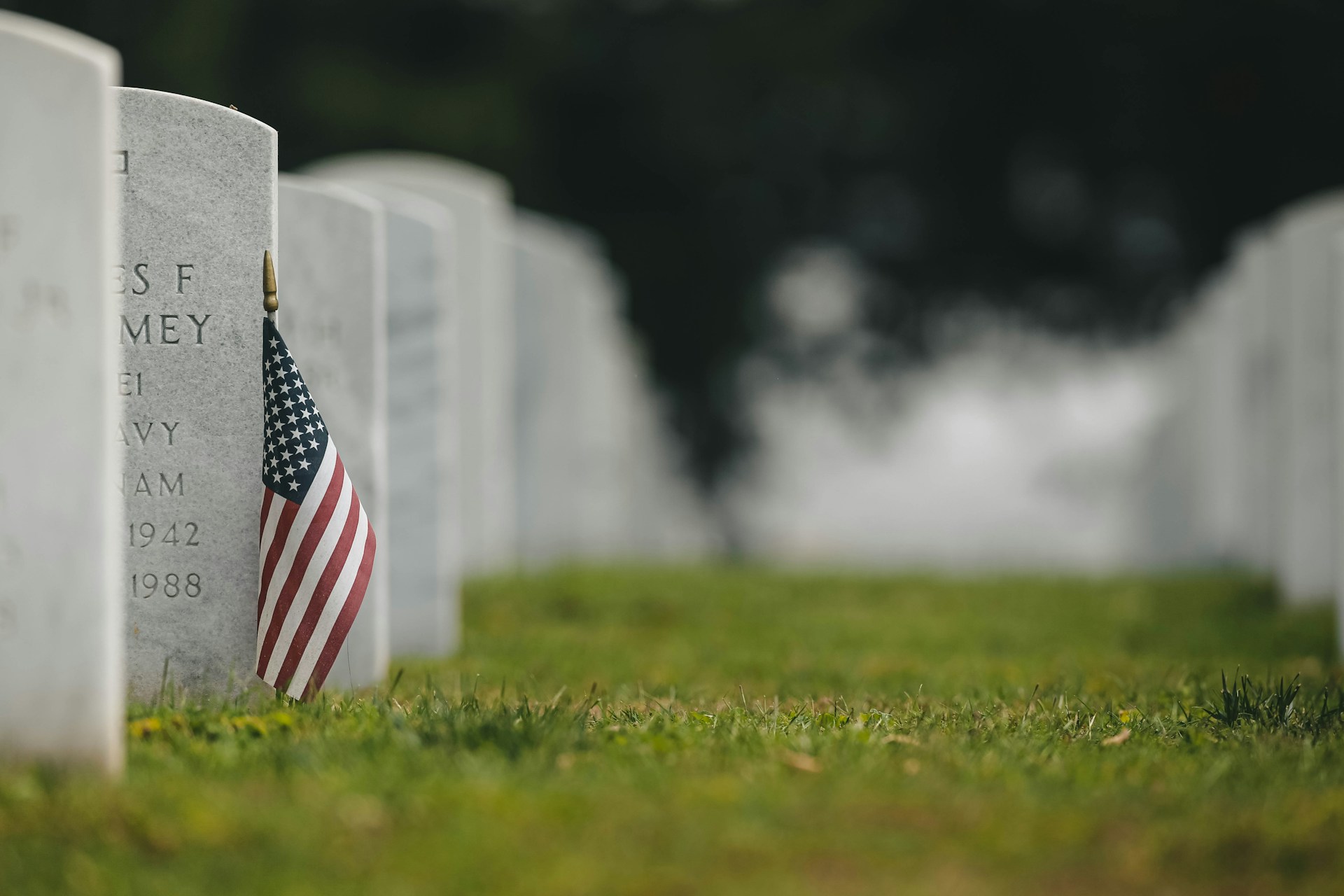 A close-up of a U.S. flag gently placed on a gravestone during Memorial Day