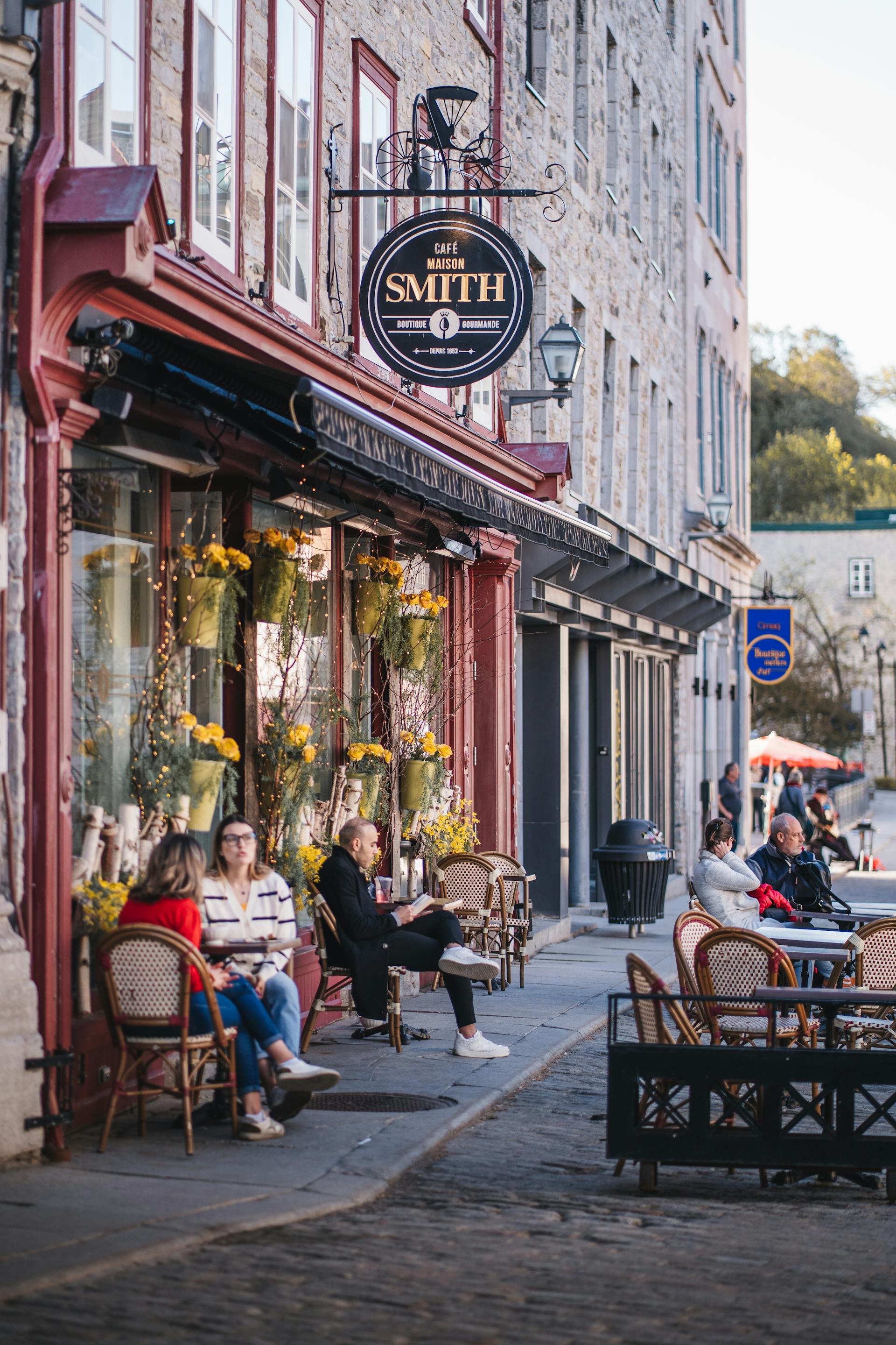 A lively street in Quebec City with vibrant storefronts and people walking along the cobblestone path.