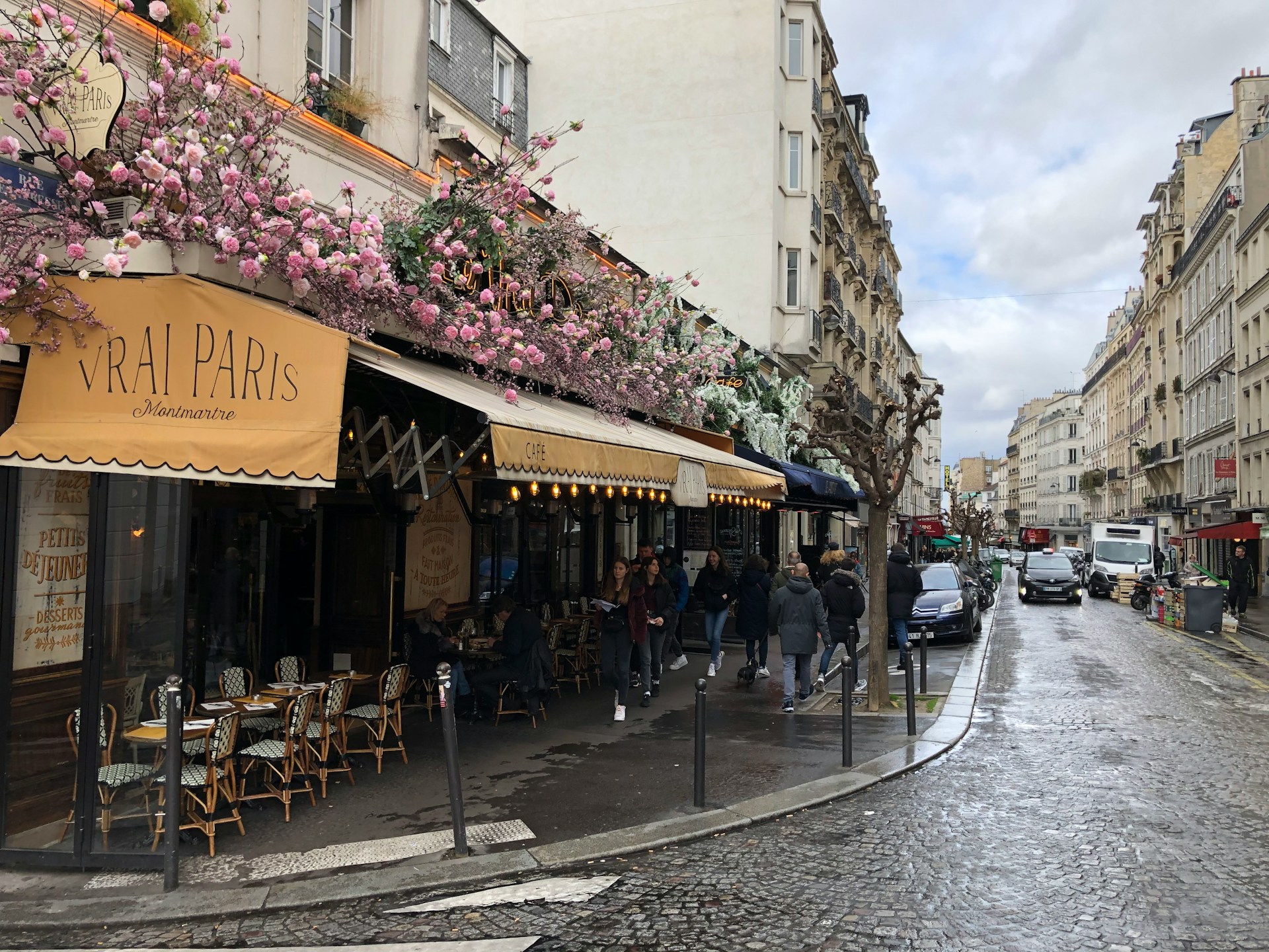 Typical Parisian street lined with Haussmann-style buildings, wrought-iron balconies, and café terraces.