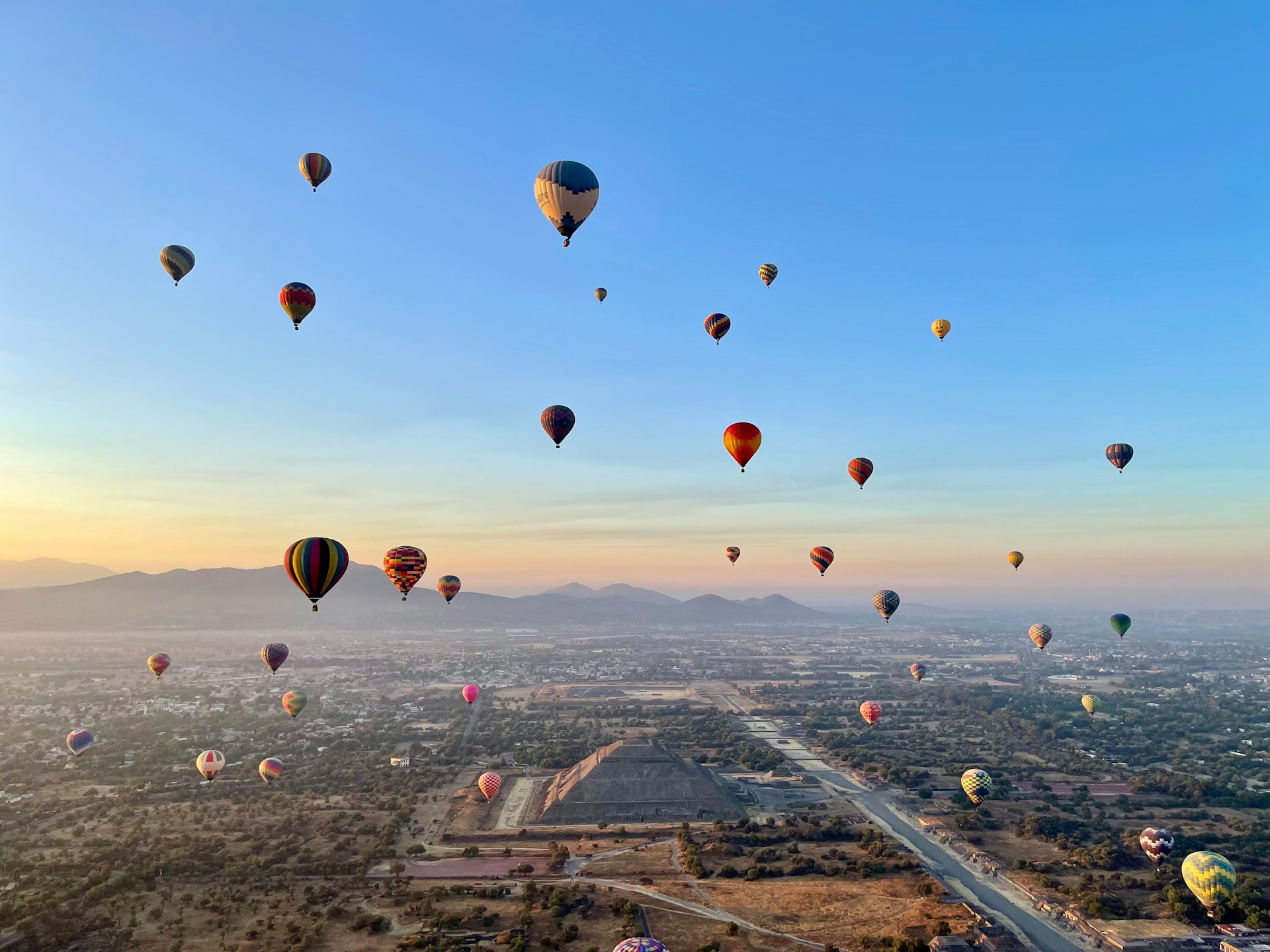A breathtaking view of Teotihuacán at sunrise, with the ancient Pyramid of the Sun and Pyramid of the Moon rising above the vast archaeological site