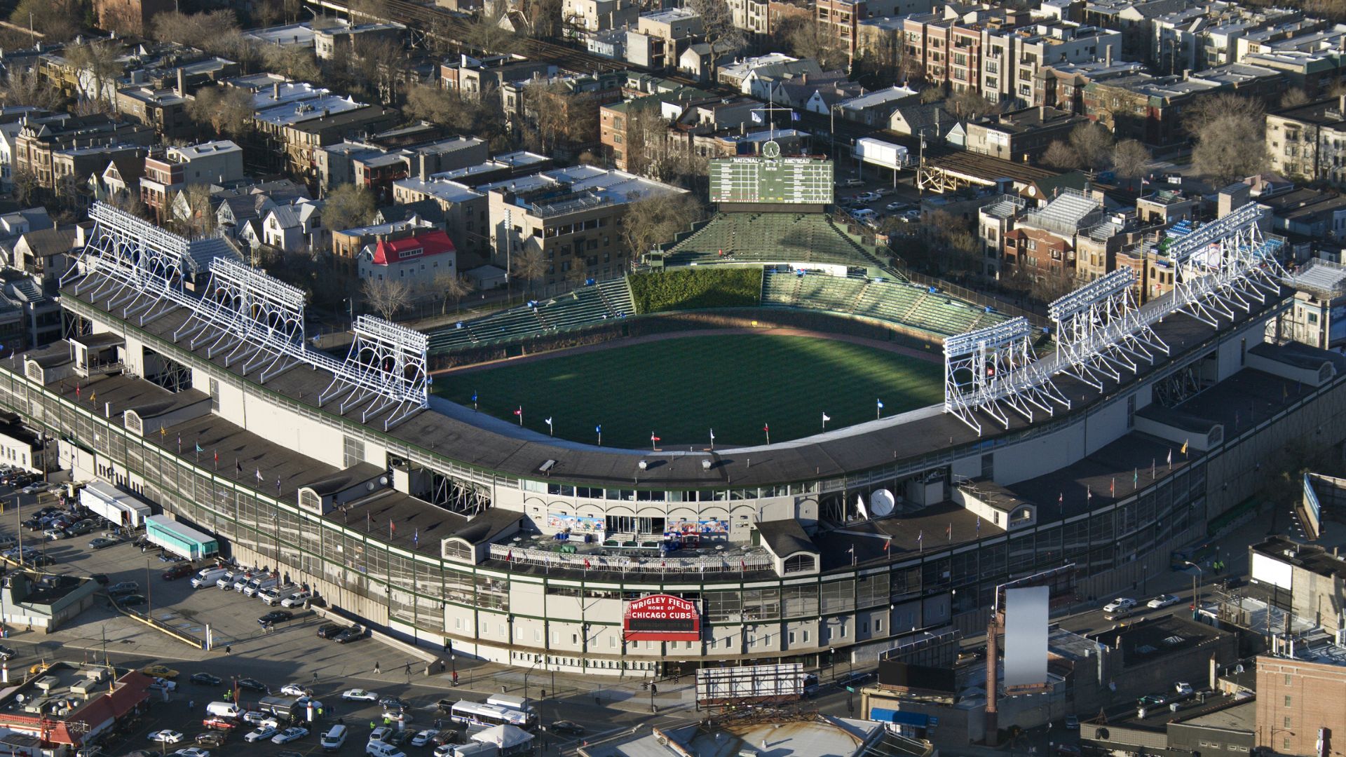 An aerial view of Wrigley Field, a historic baseball stadium in Chicago, surrounded by urban buildings and streets.