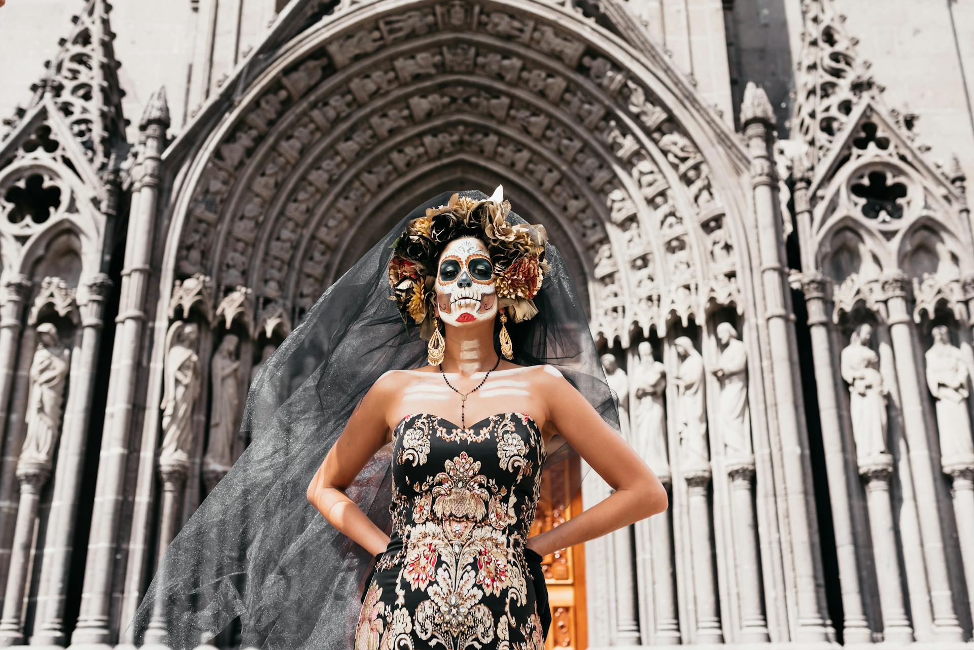 Woman wearing traditional Día de los Muertos face makeup resembling a sugar skull, with colorful floral designs and ornate detailing, celebrating the Day of the Dead in Mexico.