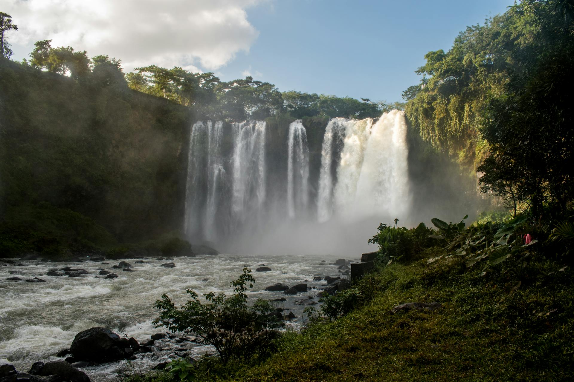 Waterfall cascading into a rocky pool surrounded by dense tropical forest in Los Tuxtlas, Veracruz.