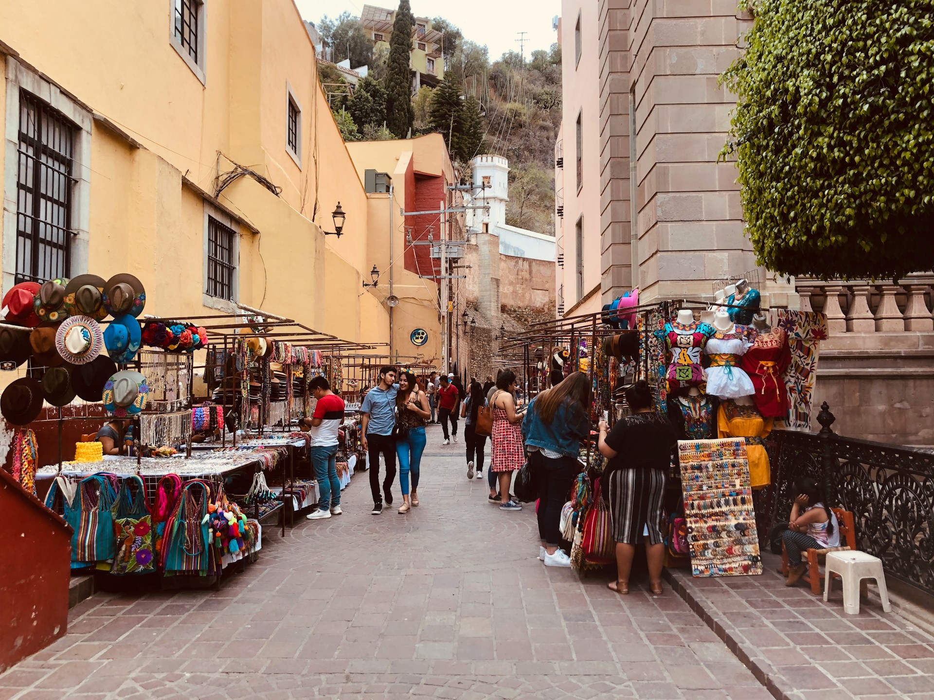 A bustling Mexico street market filled with colorful stalls selling handmade goods, fresh produce, and vibrant textiles.