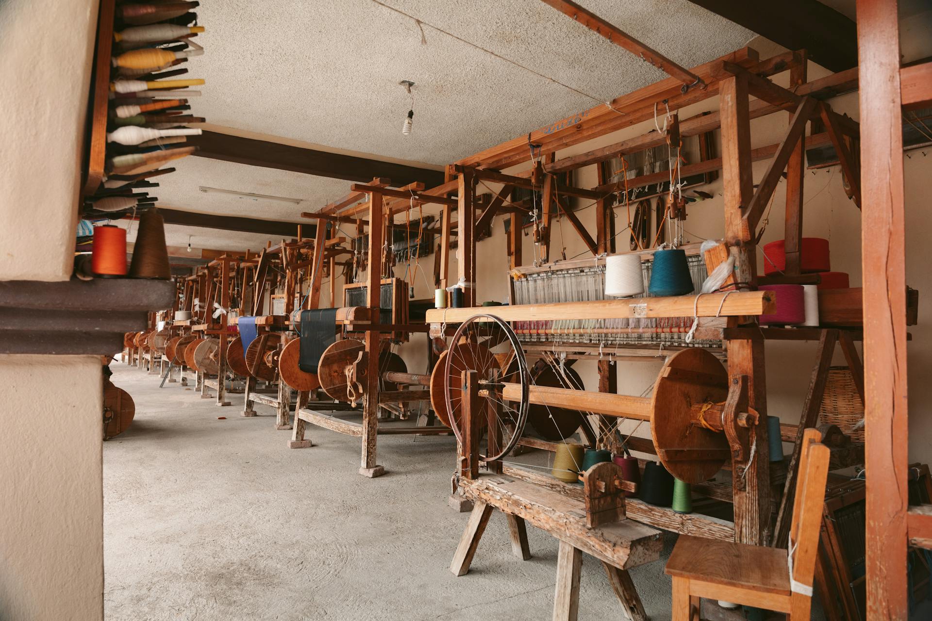 Artisan’s hands weaving dyed wool into a patterned textile on a wooden loom in a traditional Oaxacan workshop