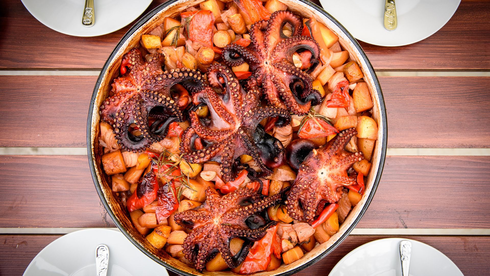 A close-up of a traditional Croatian octopus peka dish, featuring octopus and potatoes.