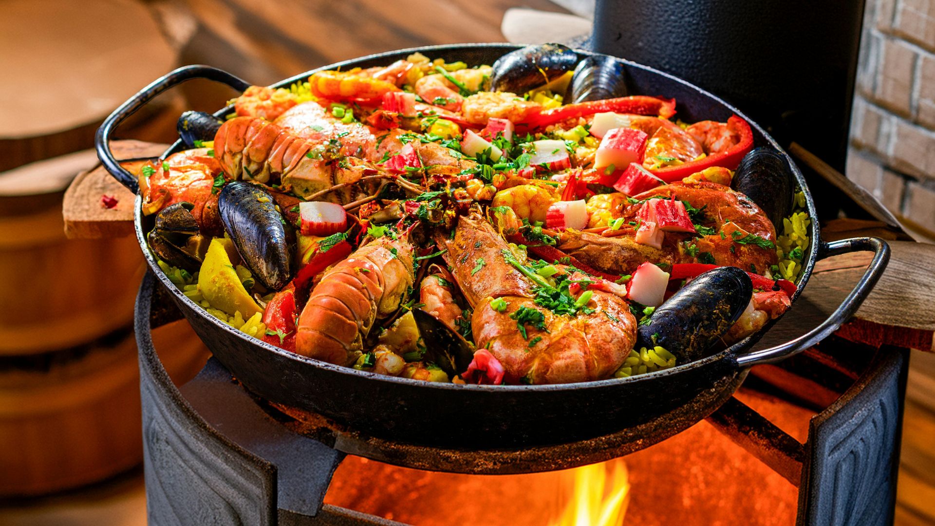 A vibrant seafood paella, brimming with shrimp, mussels, and other seafood, cooking in a large pan over an open flame. 