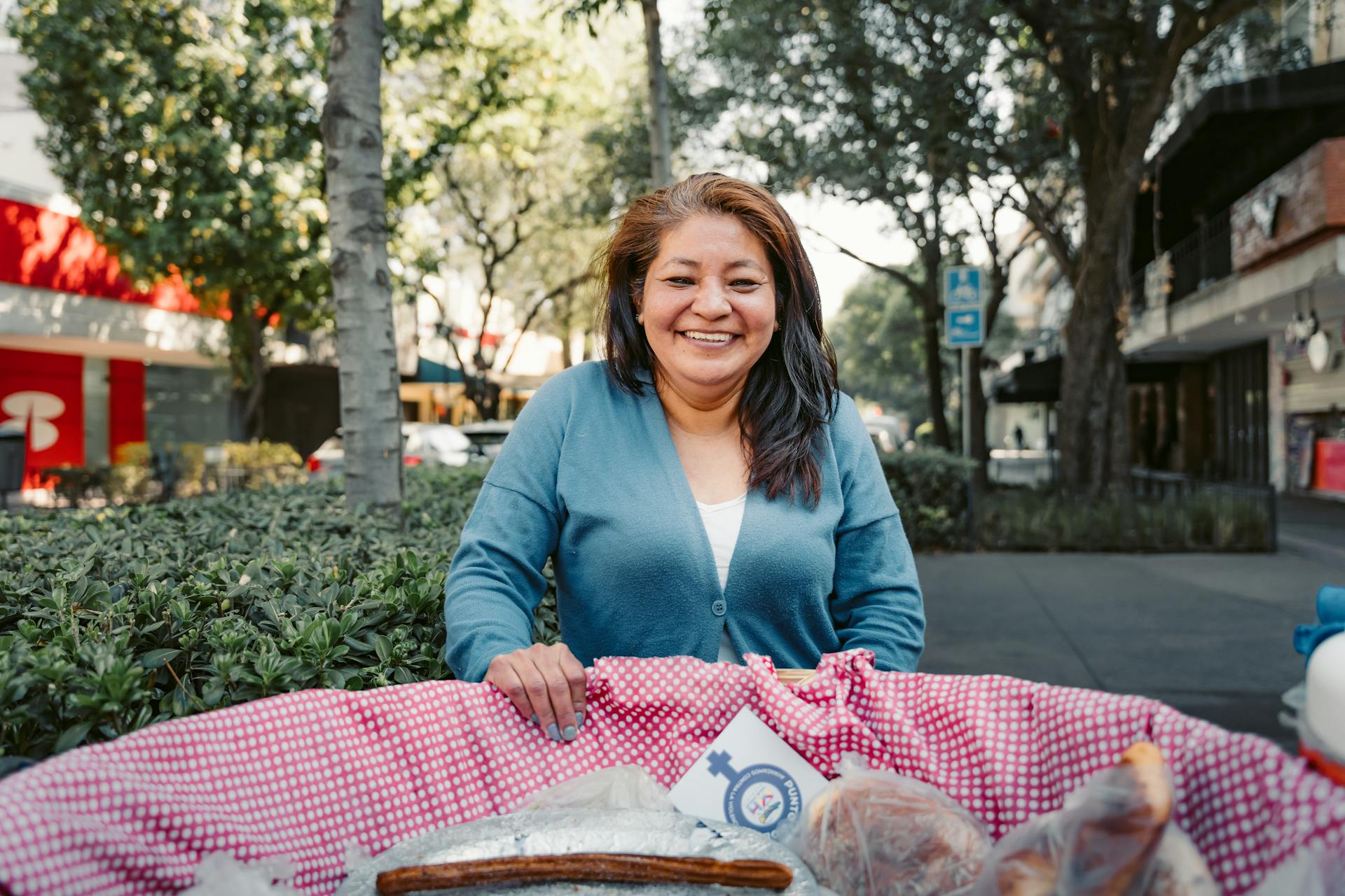 Mexican street vendor standing behind a small cart selling traditional food and snacks