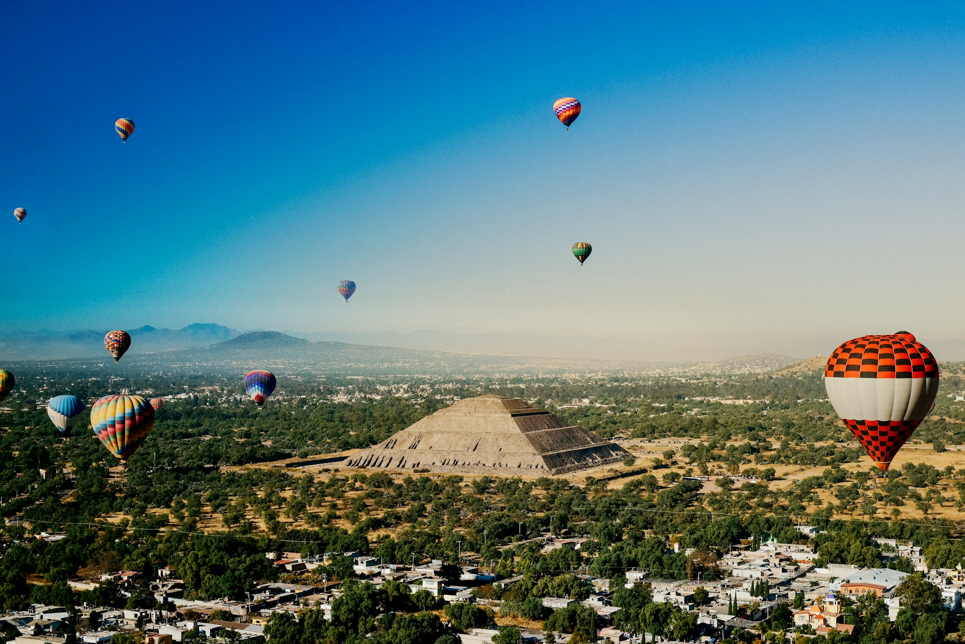 A wide view of Teotihuacan’s Avenue of the Dead, flanked by ancient stone structures, with the Pyramid of the Moon towering at the end of the grand ceremonial road.