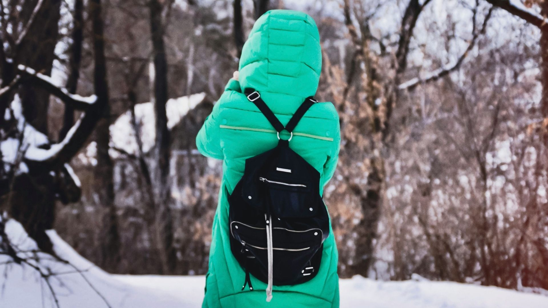 A woman wearing a green puffer jacket in a snowy surrounding