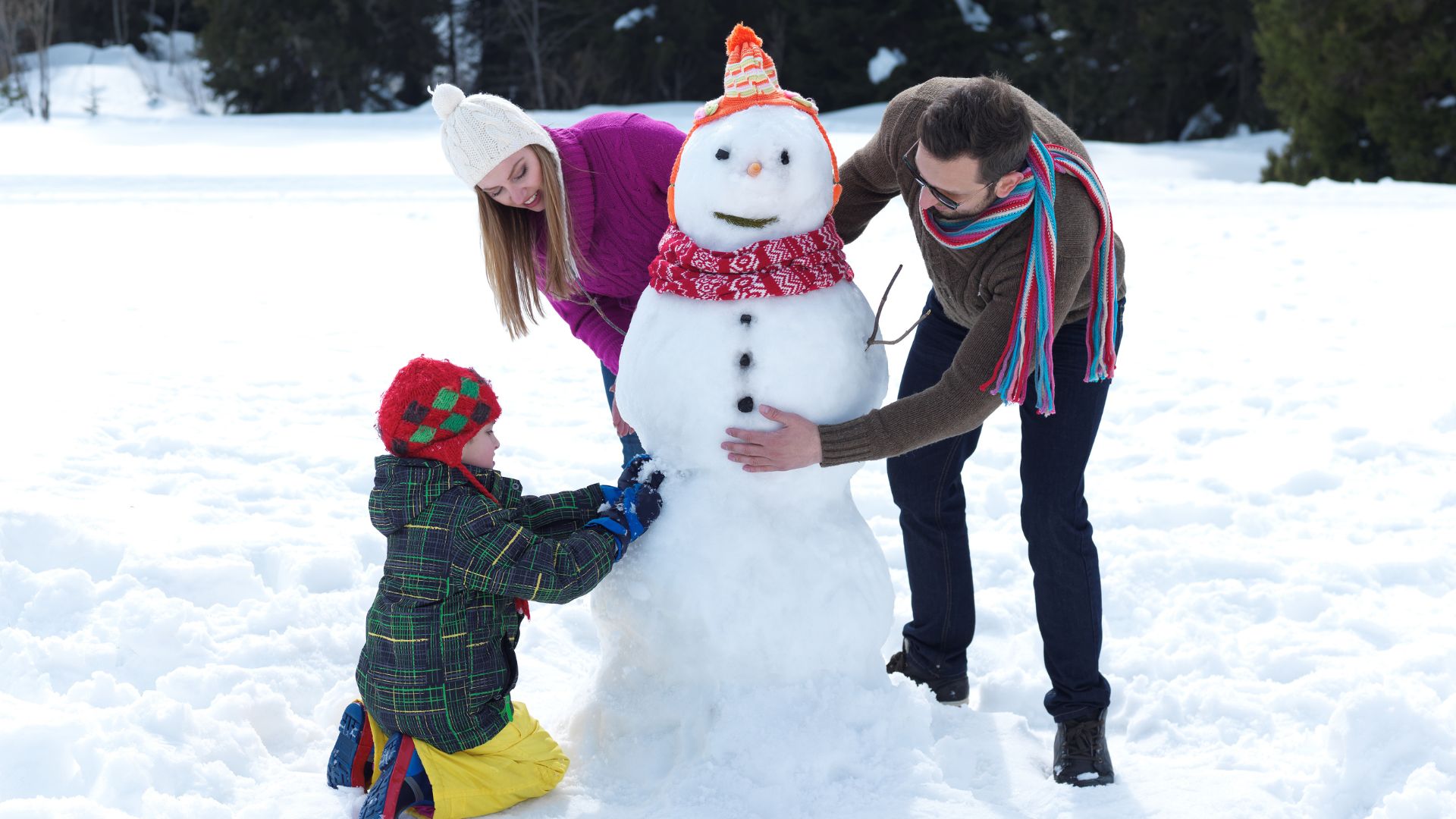 A family of tree building a snowman