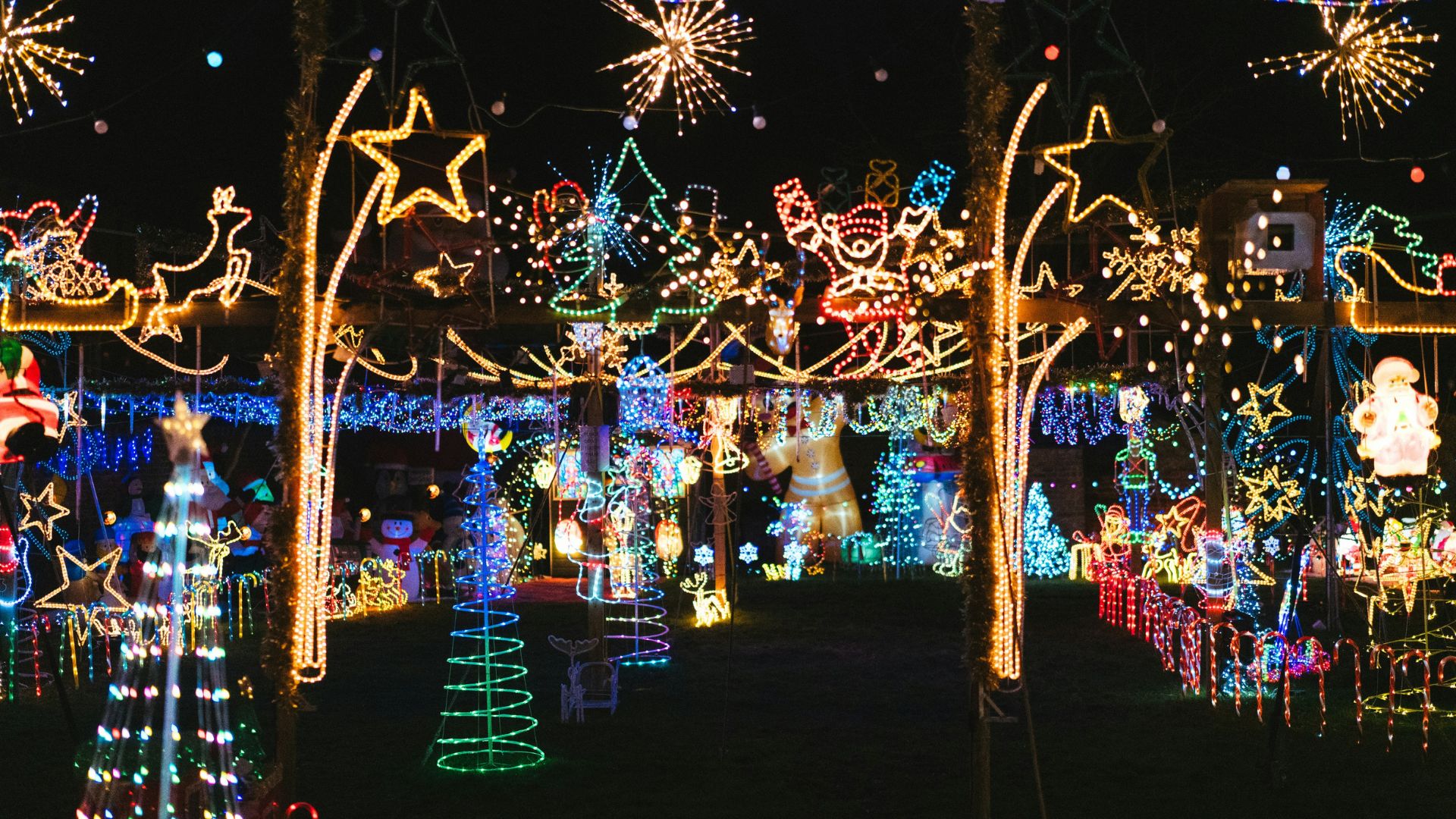 A dense, vibrant display of colorful Christmas lights and figures outdoors at night