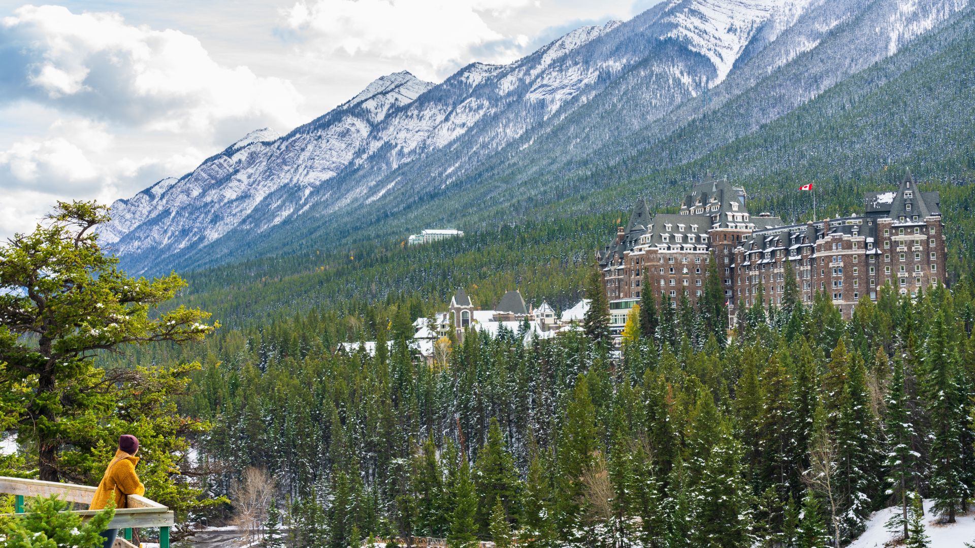 Fairmont Banff Springs Hotel in the snowy Canadian Rockies with a person in a yellow jacket in the foreground.