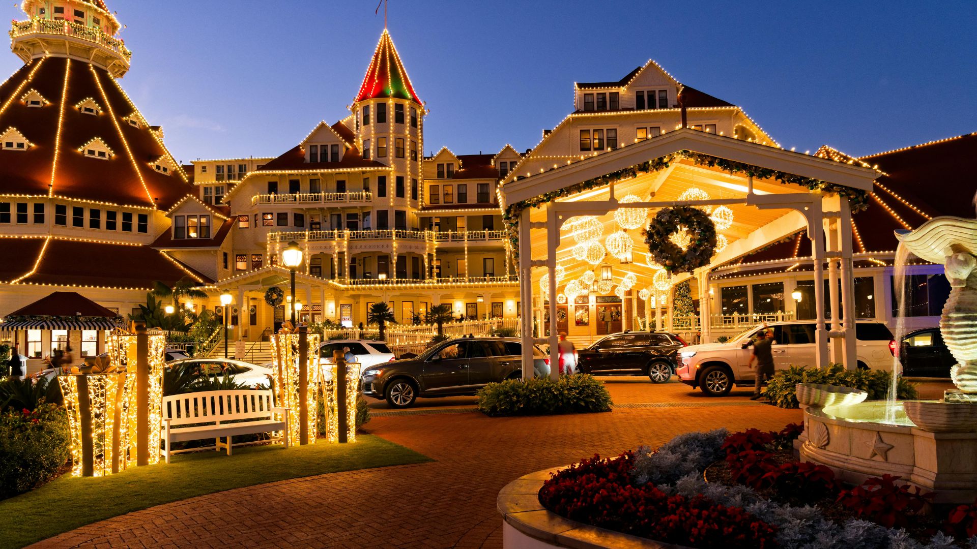 Illuminated Hotel del Coronado at dusk, adorned with holiday lights and decorations.