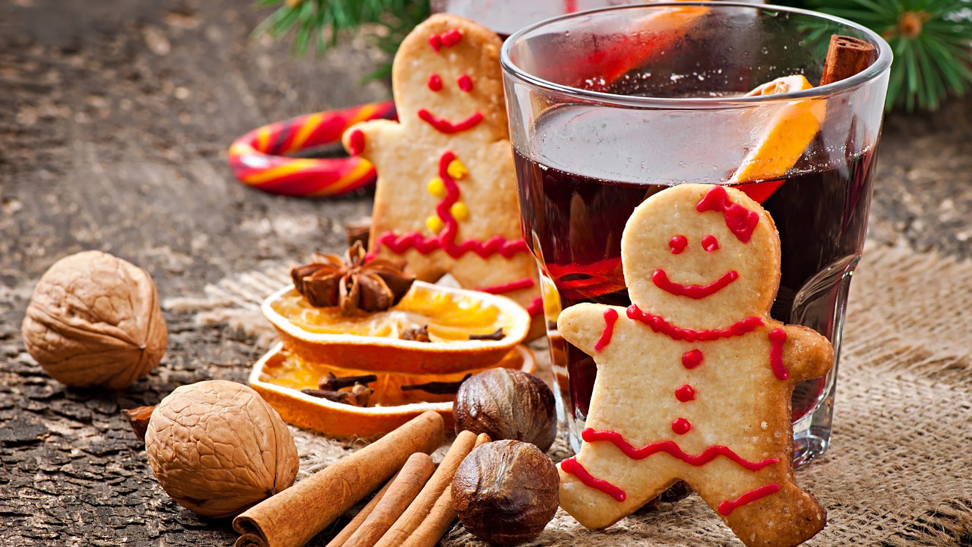 Warming mulled wine, spices and gingerbread cookies on a rustic wooden background