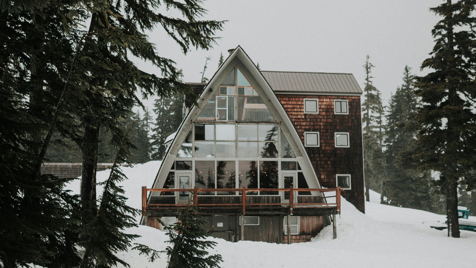 A large A-frame lodge in a snow-covered evergreen forest.