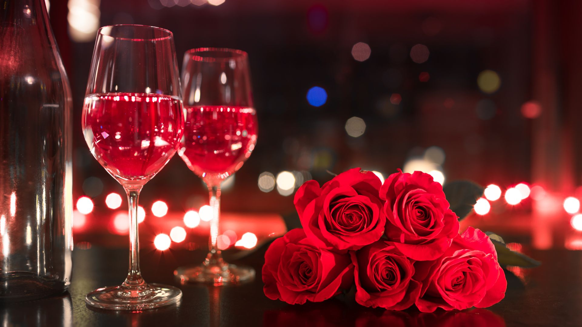 A bottle of wine, two glasses, and roses
