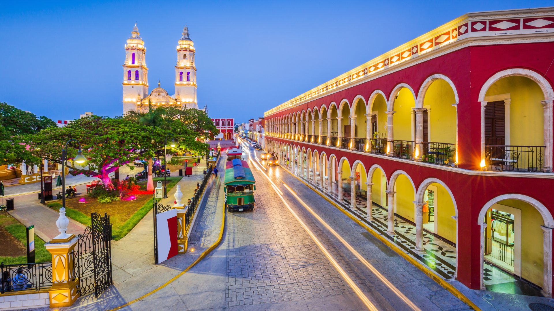 Night photo of the illuminated Cathedral of San Francisco de Campeche and colourful colonial-style buildings lining the Independence Square in Campeche, Mexico.