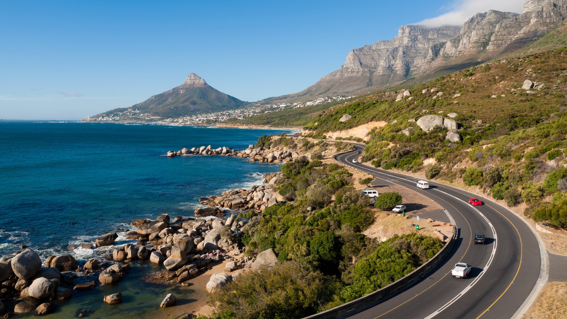 Sccenic photograph of Table Mountain in Cape Town, South Africa, overlooking a coastal road and the ocean.