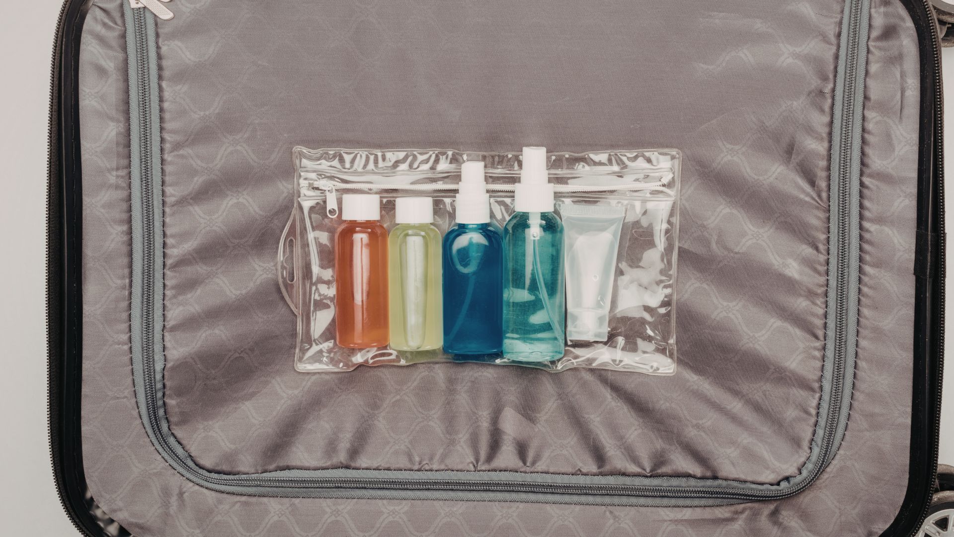 A screenshot of a graphic design workspace showing a transparent travel toiletry bag containing several small bottles.